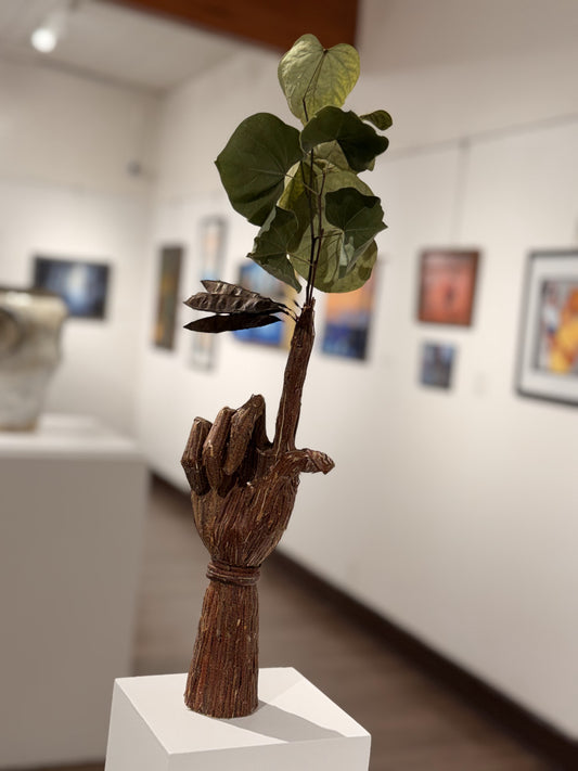 Charlie’s Tree, a sculpted hand covered in redbud bark holding green leaves and seed pods, by McKlveen.